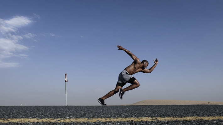 Topless Man Wearing Grey And Black Shorts Sprinting On Concrete Road